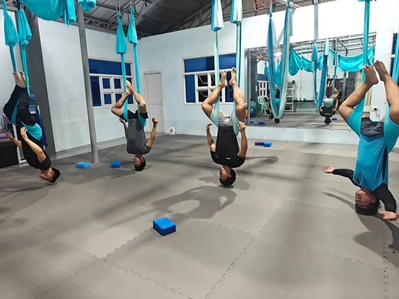 An aerial yoga class at Altair Studio with students inverted in teal hammocks
