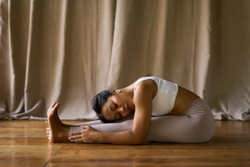 A yoga practitioner in a seated forward fold on the wooden floor at Anahaw Dauin