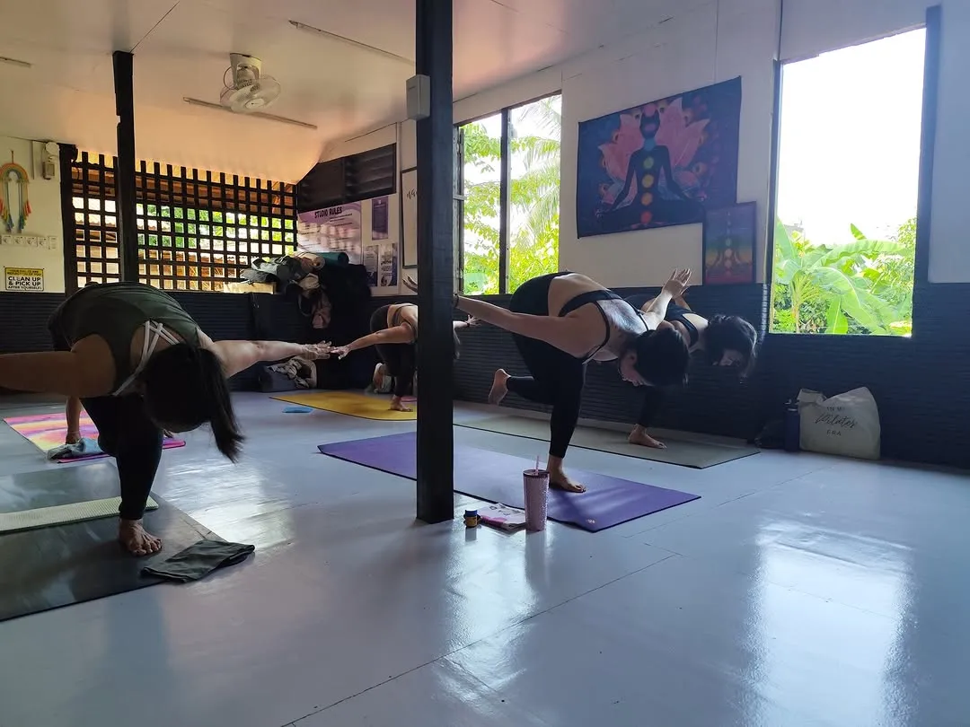 Students folding forward by the open windows at Balay Yoga