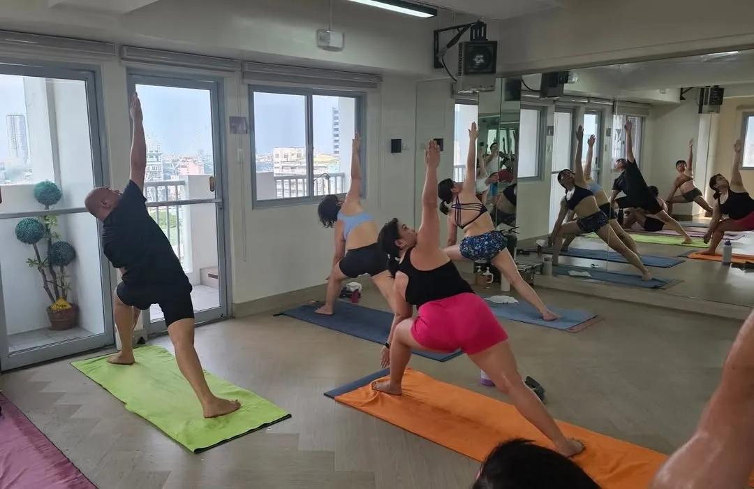 Students in standing poses beside the windows of the hot room at Bikram Yoga Manila QC