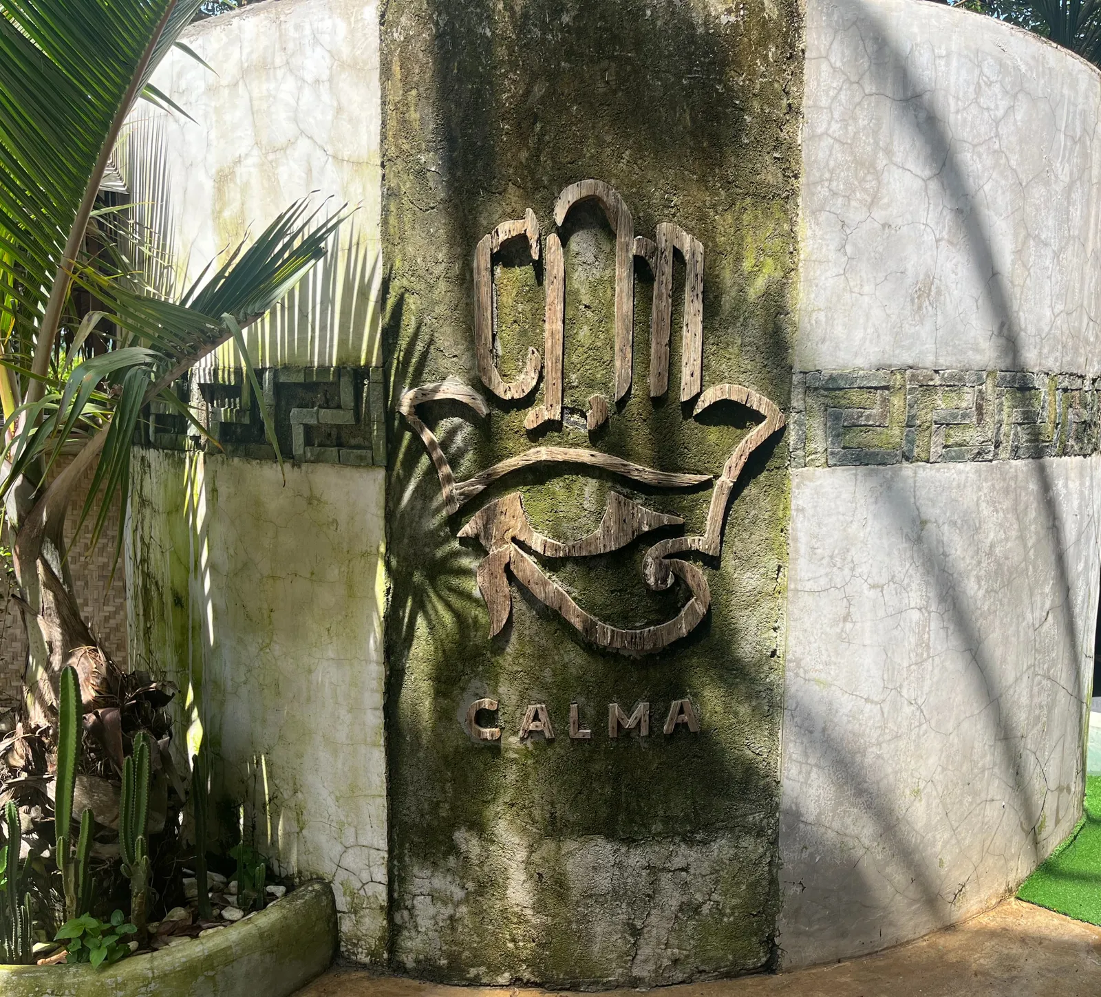 The carved Calma sign on a stone wall among plants