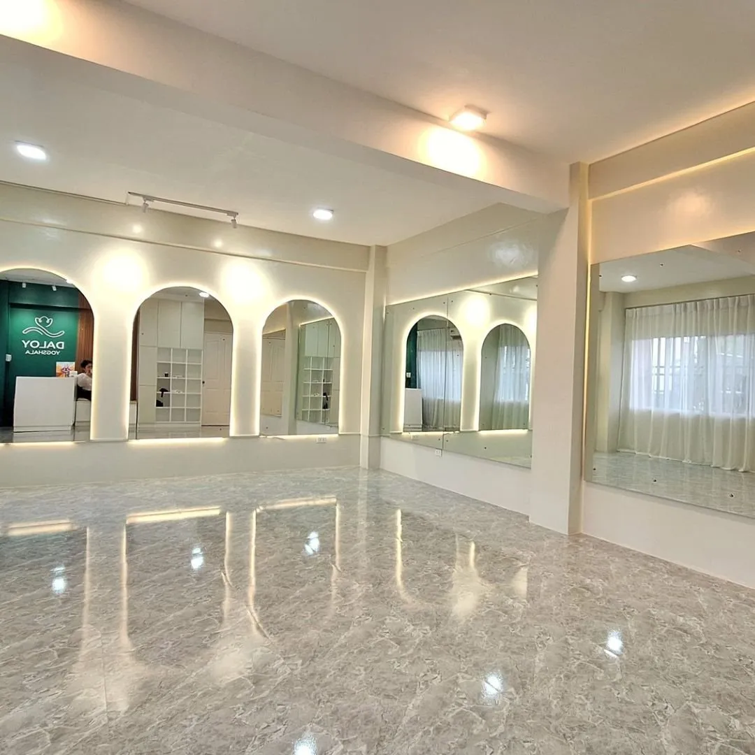 Arched mirrors and window light across the marble floor at Daloy Yogshala