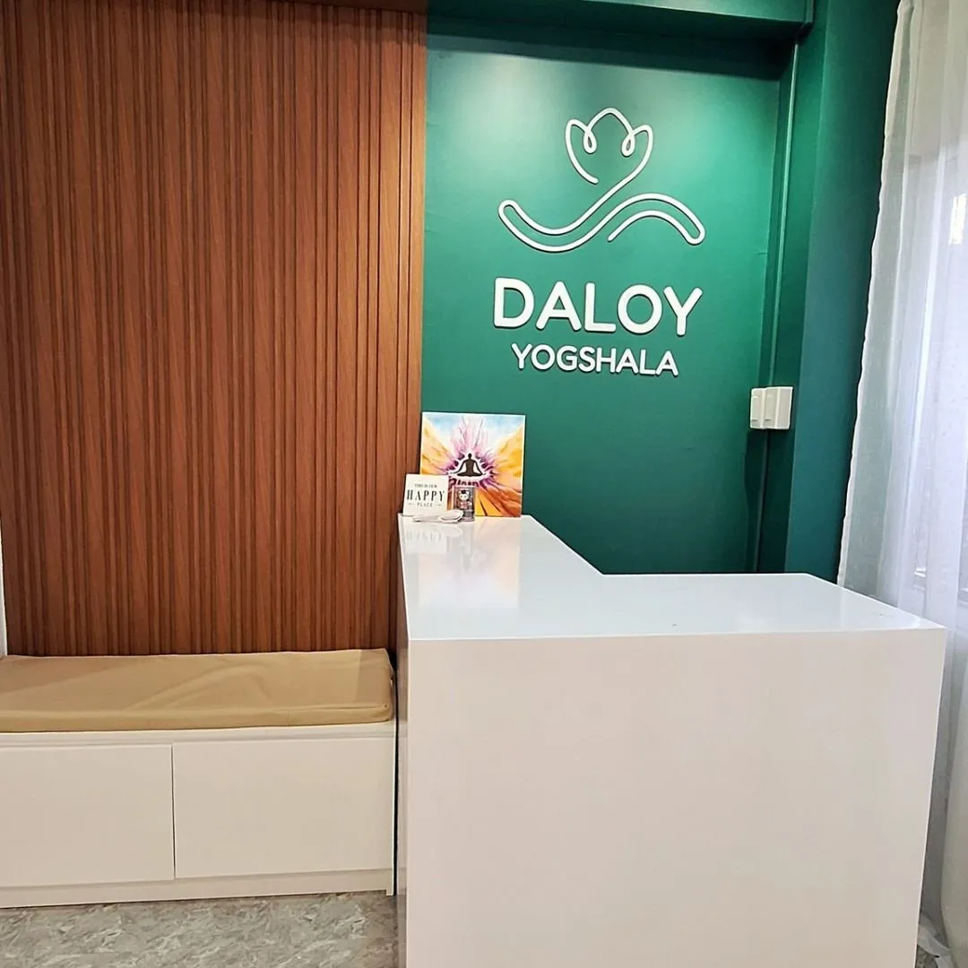 The green Daloy Yogshala logo wall above the white reception counter