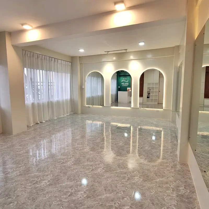 The empty practice room at Daloy Yogshala with marble floor and arched mirrors