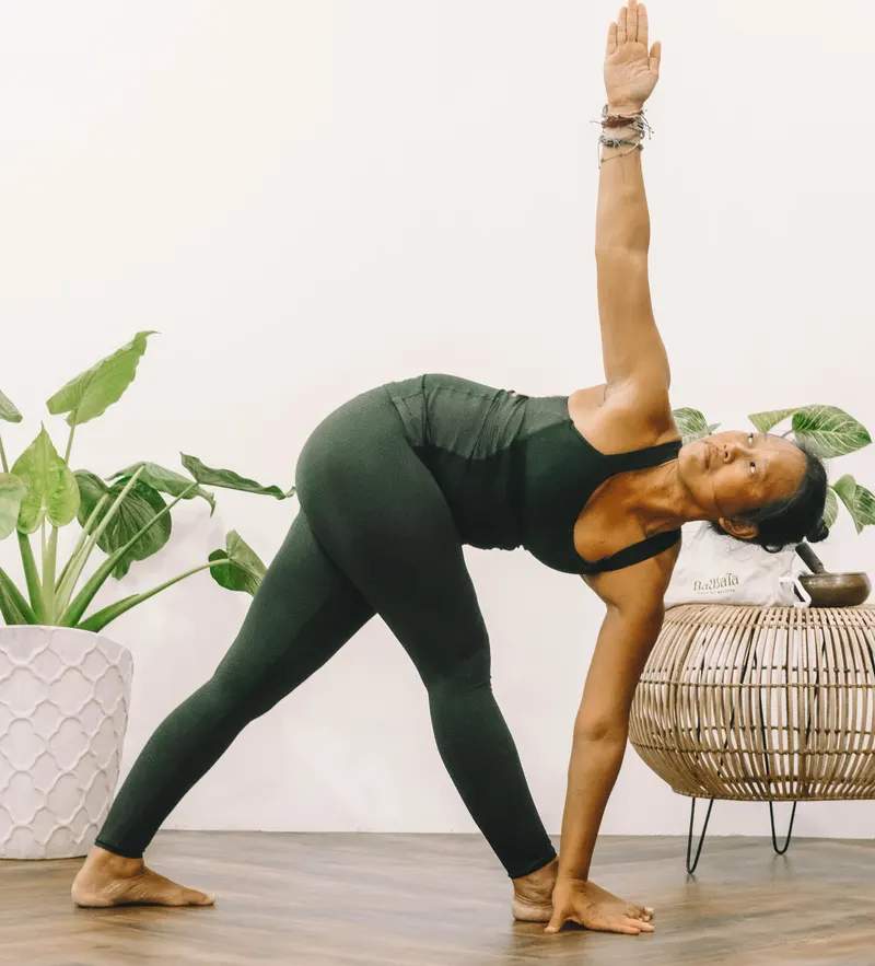 A Dawata Wellness teacher in triangle pose in the plant-filled studio