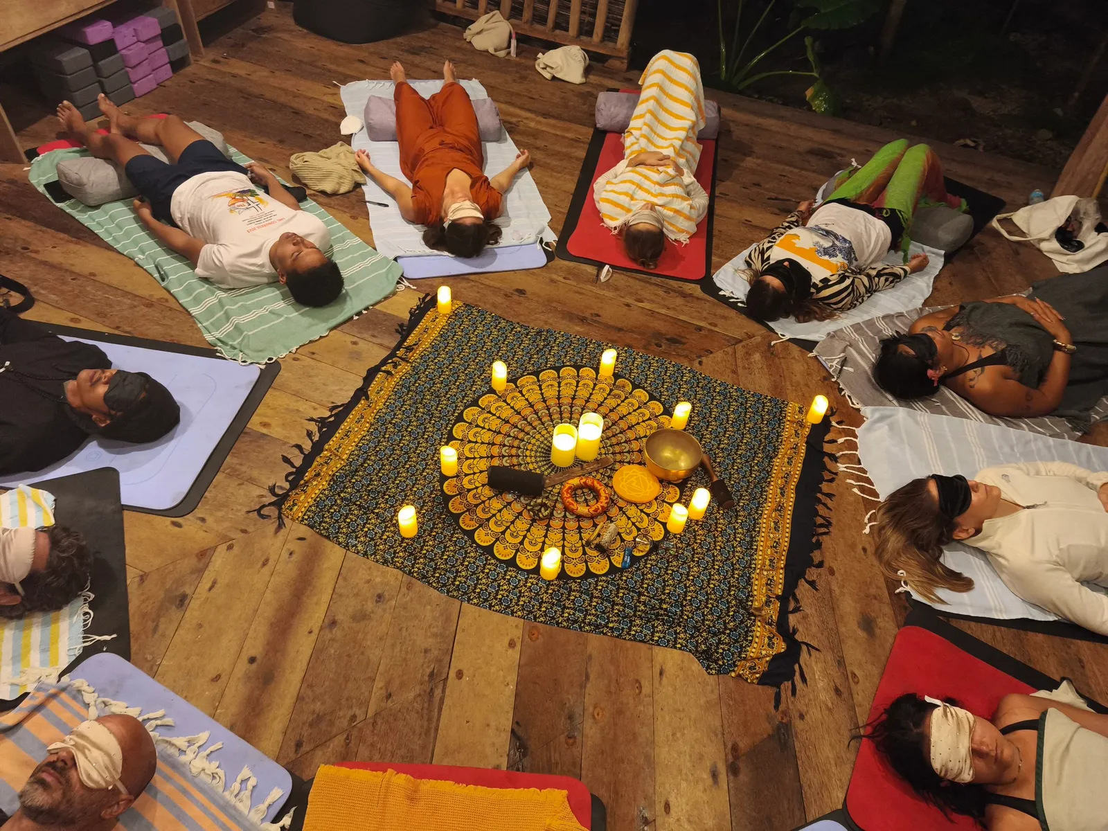 A candlelit breathwork circle on the wooden shala floor at Emerald House Village
