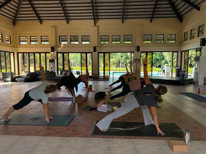 A Flow and Recovery class in triangle pose under a high-roofed open pavilion
