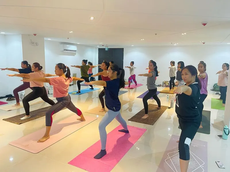 A Healing Iloilo class in warrior pose in a bright white studio