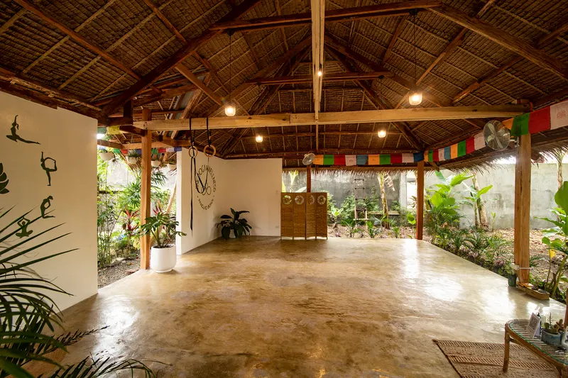The empty open-air shala at Jing Yoga and Wellness with a polished floor and thatched roof