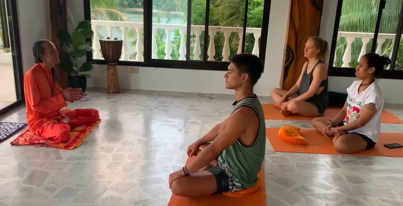 A small class seated on mats in the window-lined practice room at Kalyani Yoga Puerto Galera