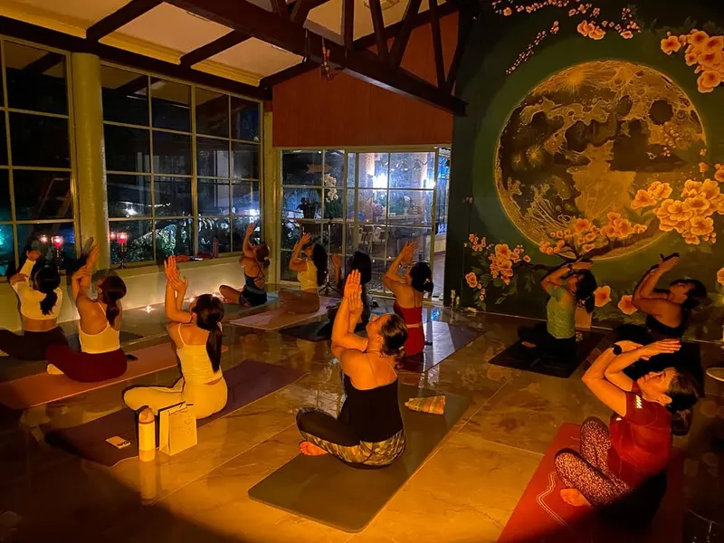An evening class in the warmly lit studio with a moon mural at Kind Flow Studio