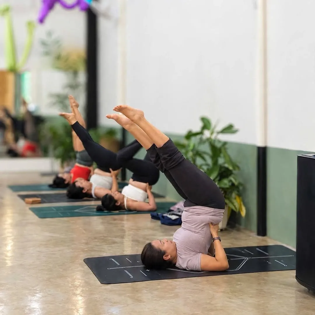 Students in shoulder stands along the mirrored wall at Love Yoga World