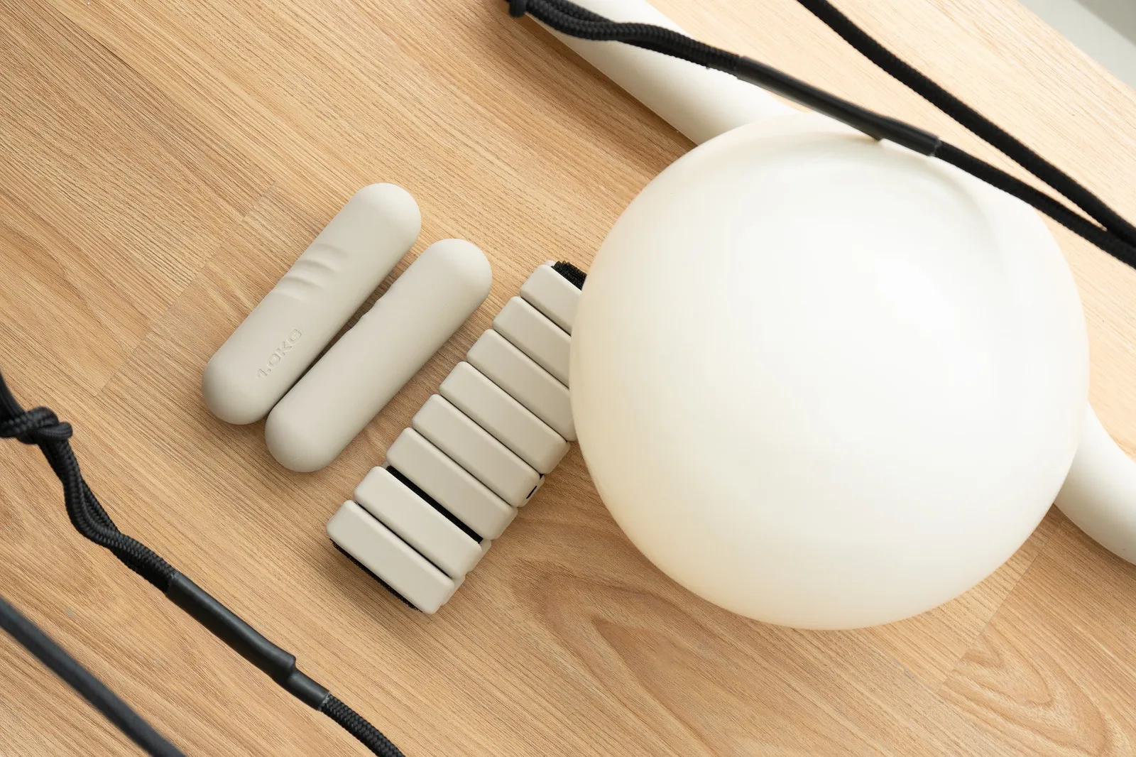 Pilates props: a soft ball, small weights and a resistance band on a wooden floor