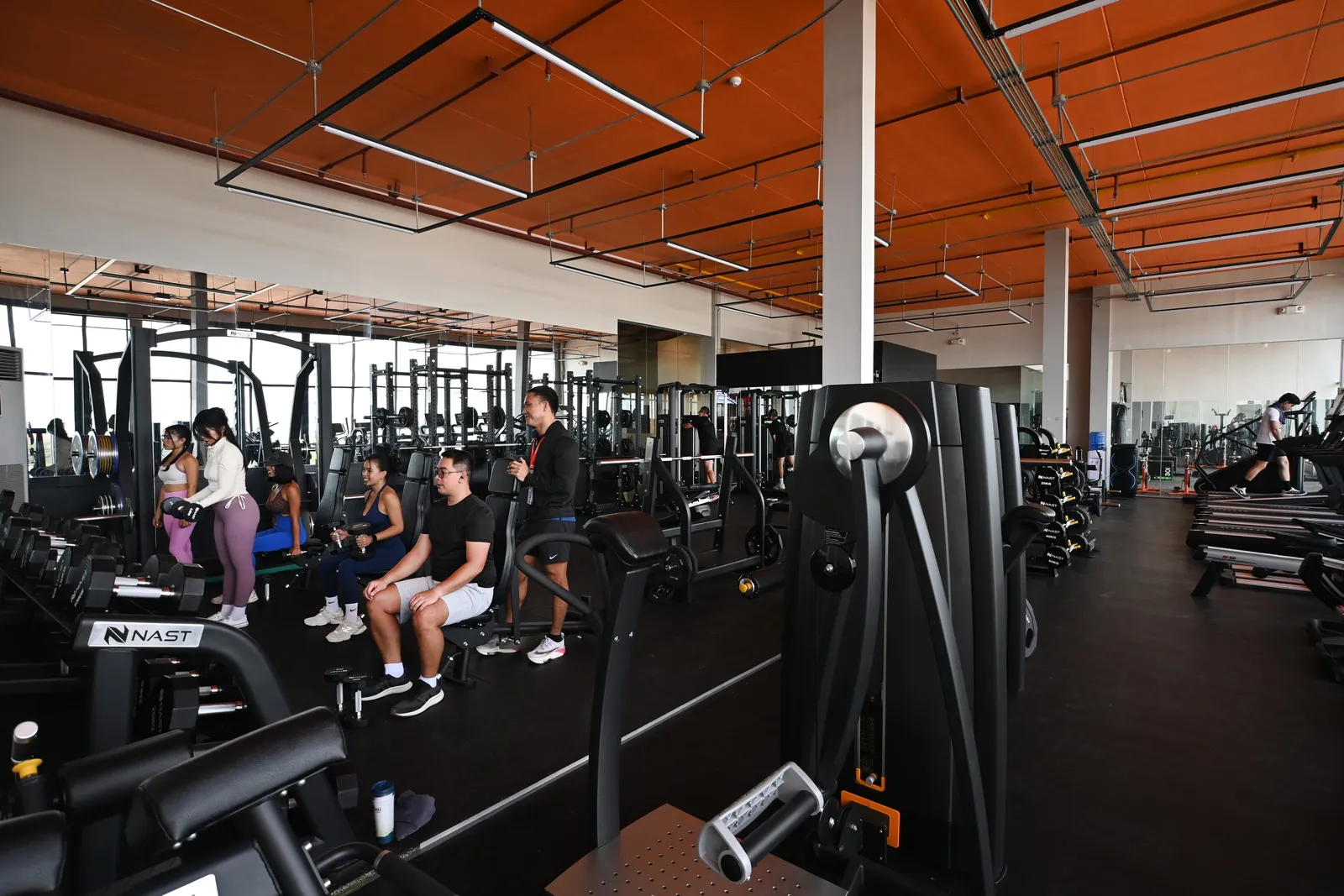 Large gym floor with machines and orange ceiling beams
