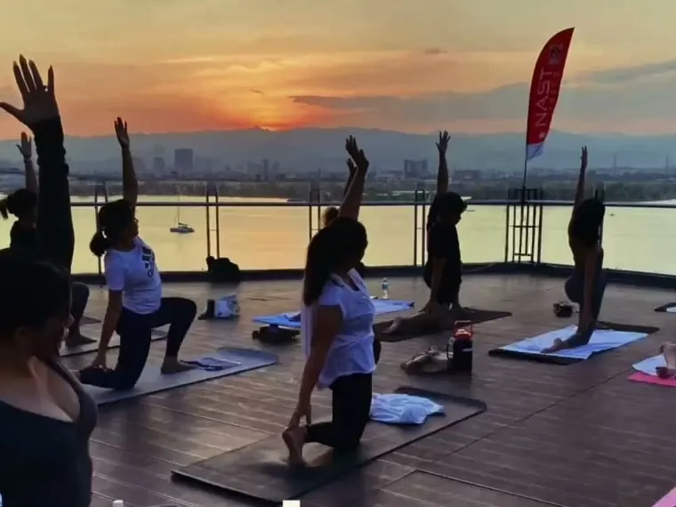 Rooftop yoga class at sunset with a view over the water
