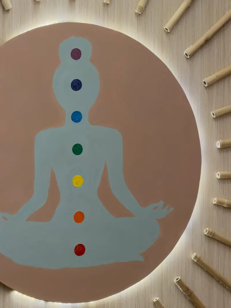 Backlit chakra wall art of a seated meditator on a studio wall