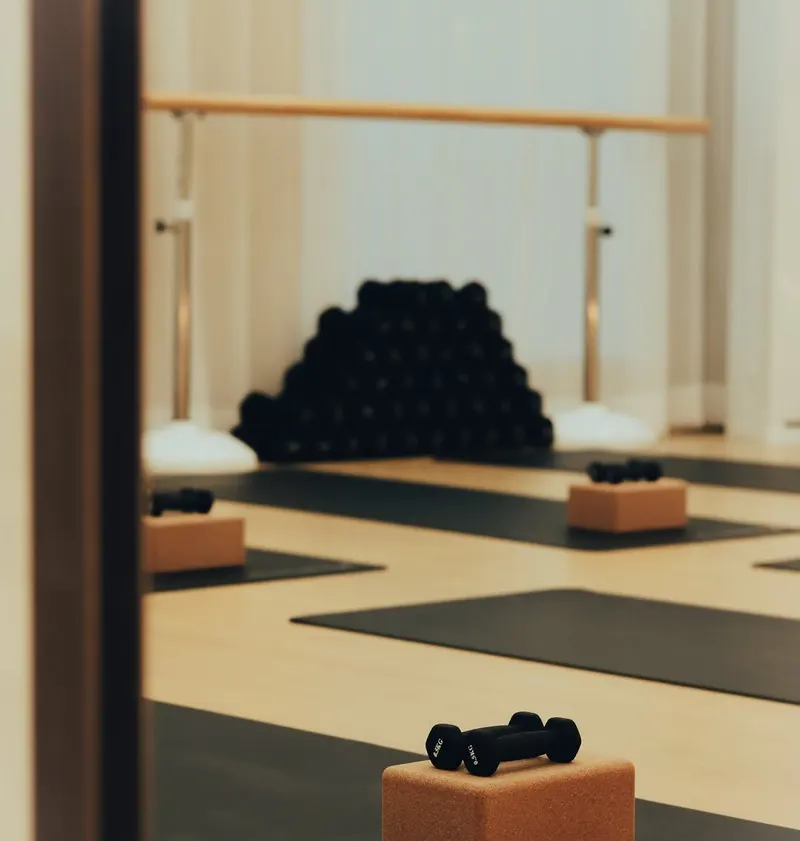 Studio floor with mats, cork blocks and dumbbells, shelves of props behind