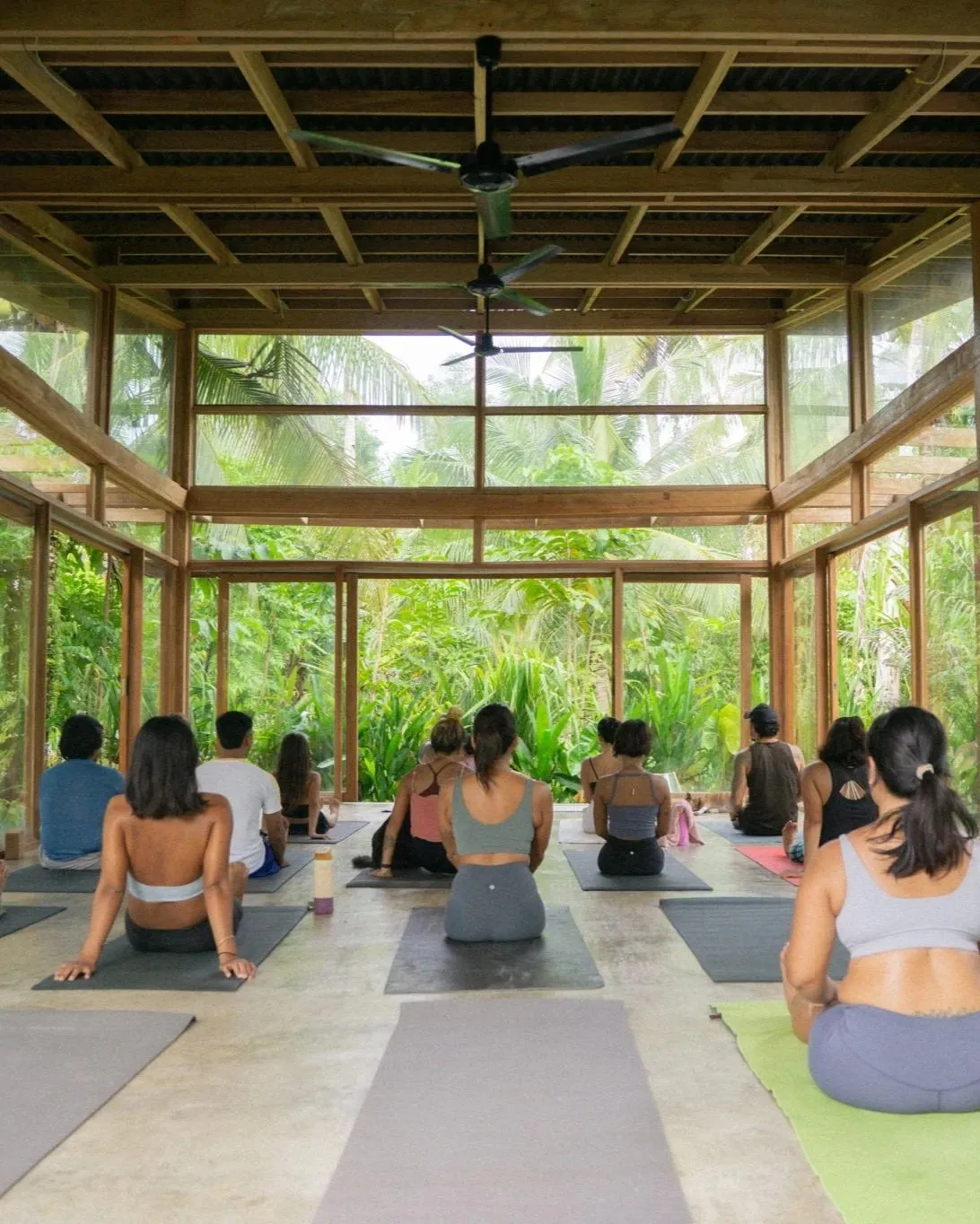 Seated class in an open wooden shala, seen from behind