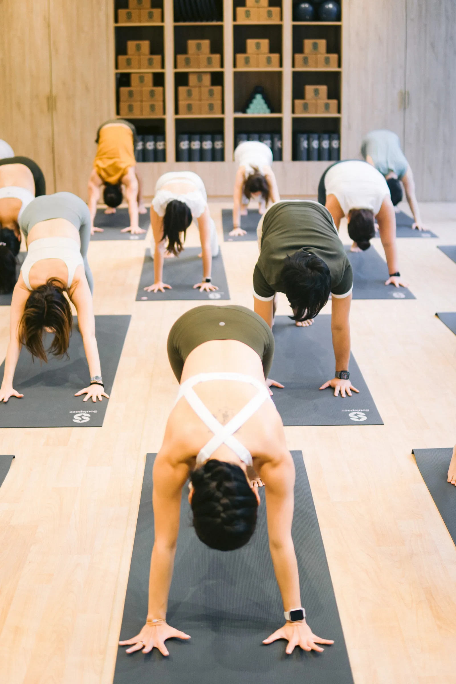 Class in downward dog on mats in front of the prop shelves