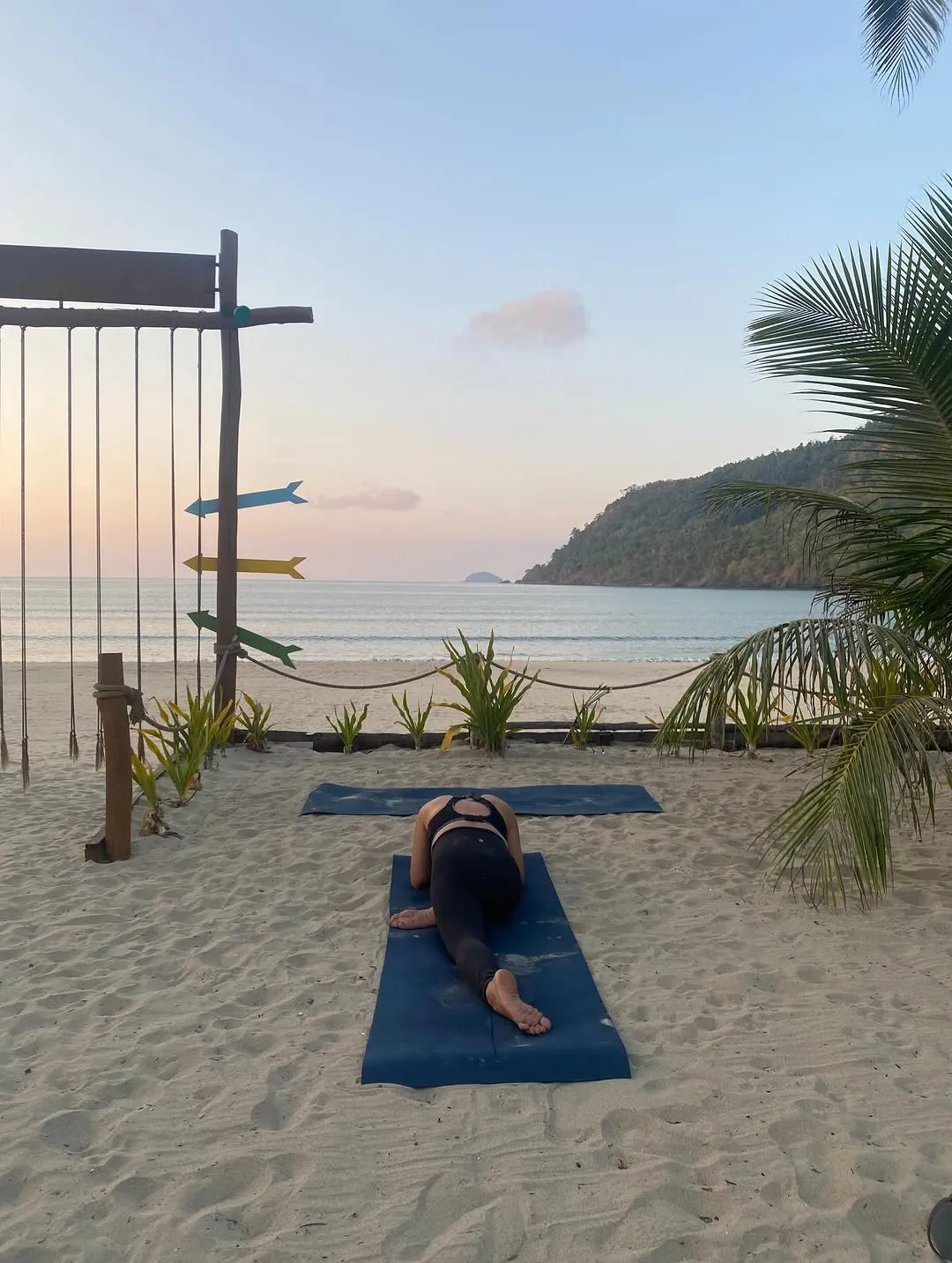 Practitioner on a mat on the beach at sunset
