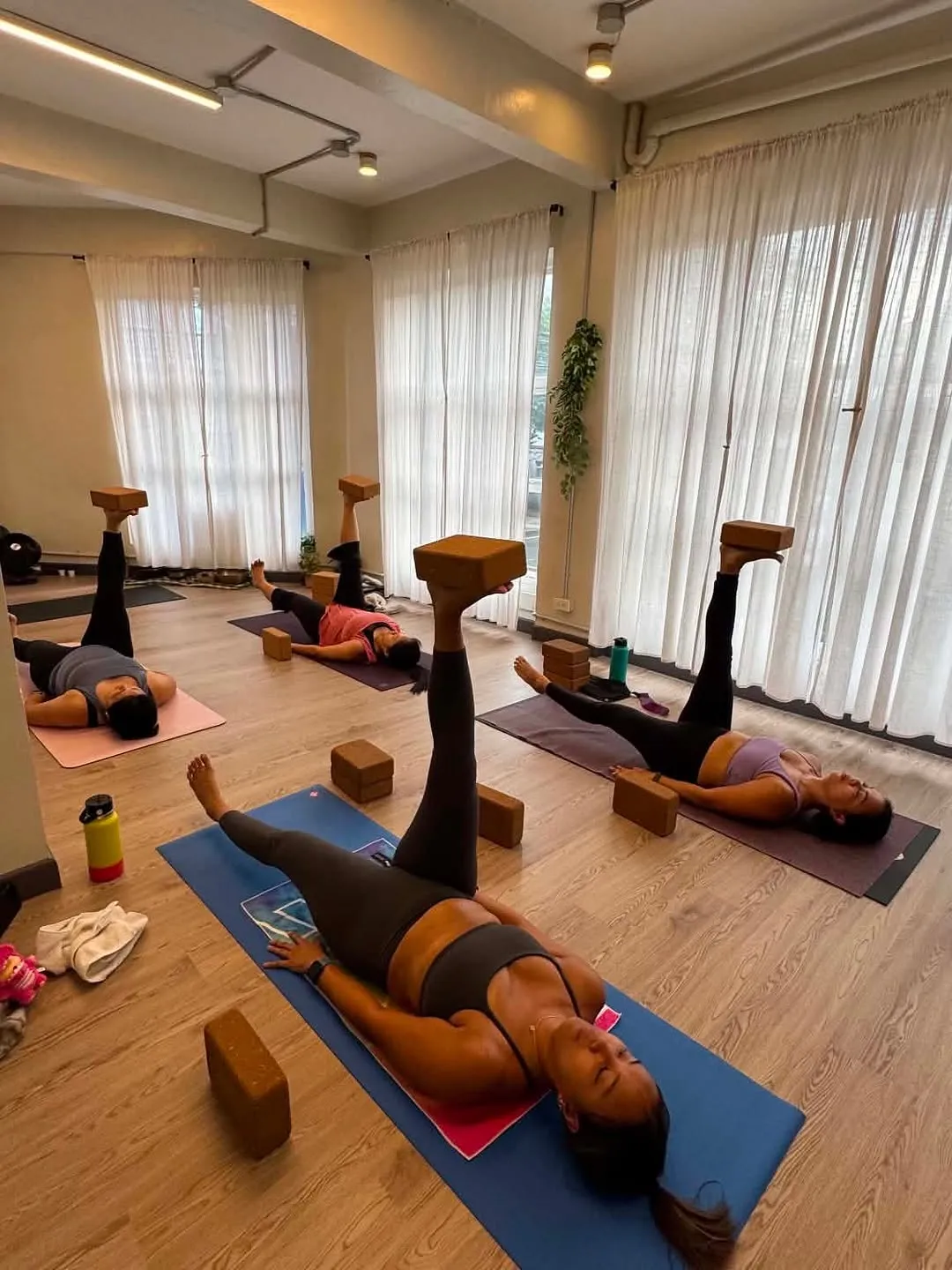Students lying on mats with legs raised on blocks during class