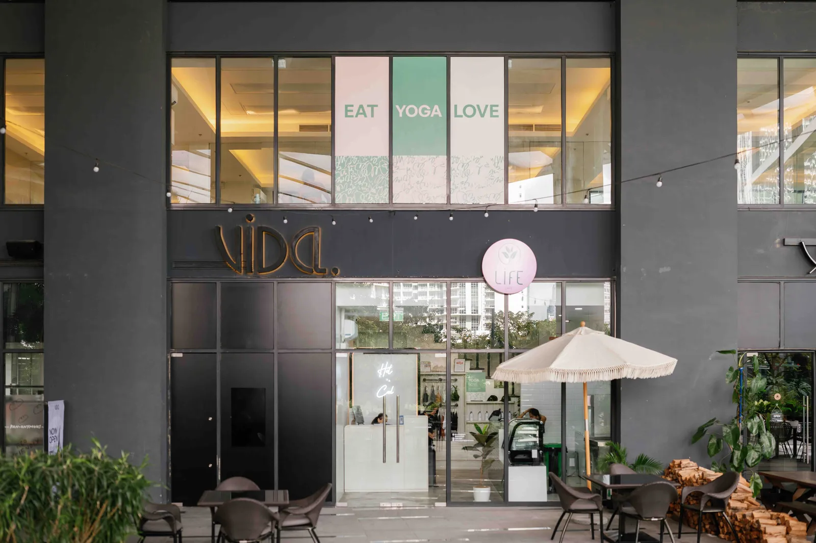 Glass-fronted studio entrance with the VIDA sign and an outdoor table under an umbrella
