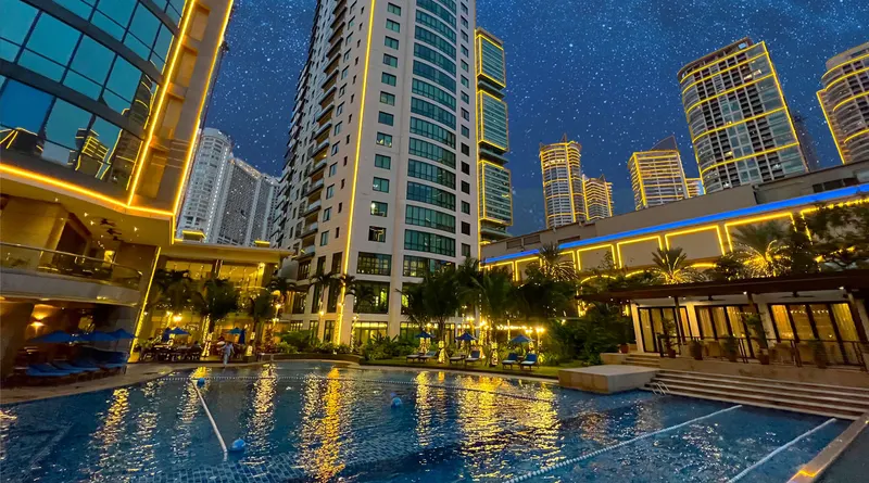 Residential towers and a lit swimming pool at night