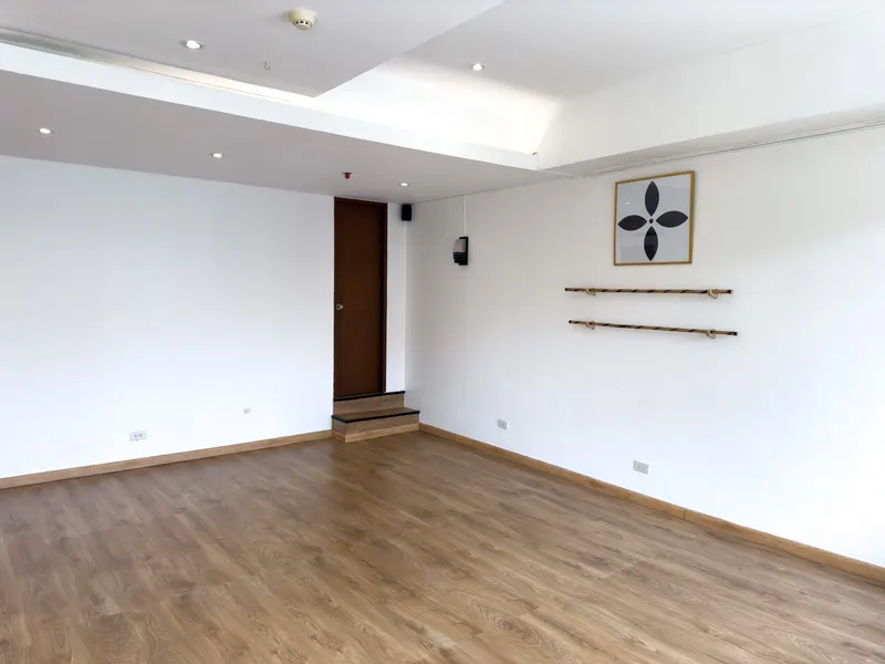 Empty studio with wooden floor, white walls and a wall-mounted bar