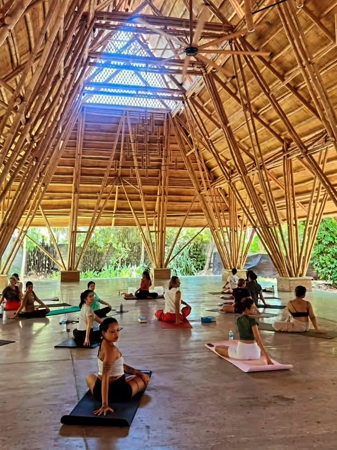 Class on mats under a soaring bamboo pavilion roof