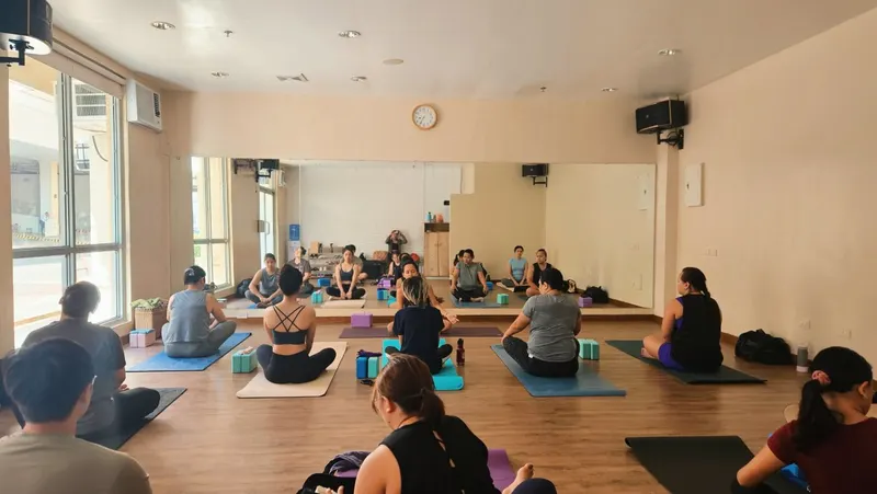 Seated class on mats in a mirrored studio with large windows