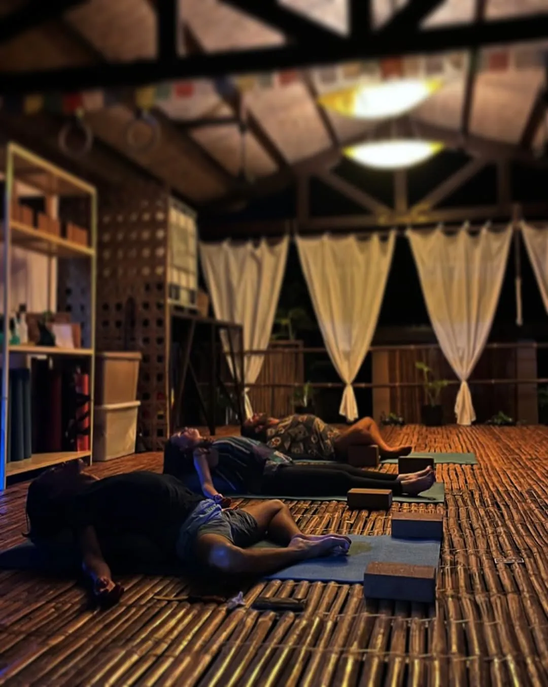 Students resting on mats in the bamboo shala at night